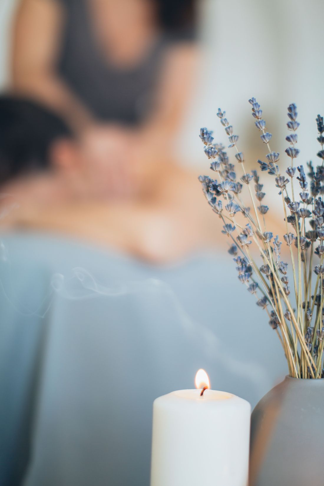 Ambiance apaisante : bougie, lavande et massage en arrière-plan